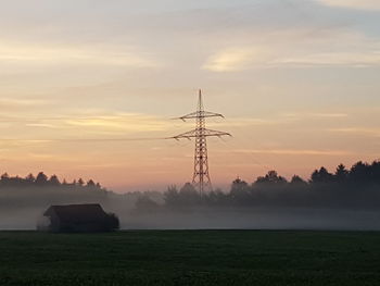 Electricity pylon on field against sky during sunset