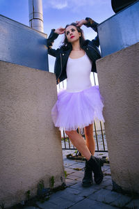 A ballerina in a tutu stands between the supports, leaning on her hands and throwing her head back