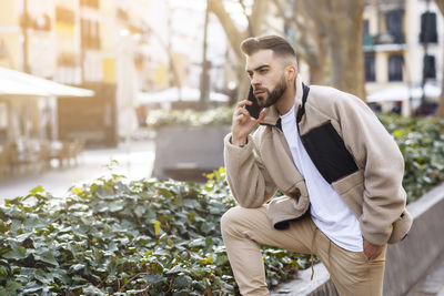 Portrait of a young man talking on the mobile phone while waiting person
