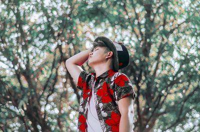 Young woman looking away while standing on tree in forest