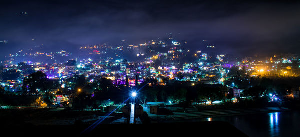 Illuminated cityscape against sky at night