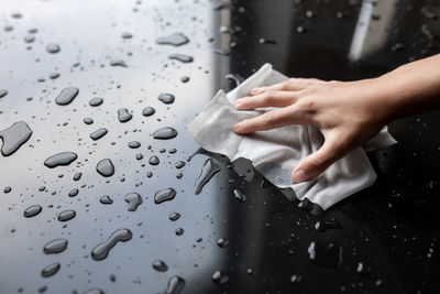 Close-up of hand touching wet glass