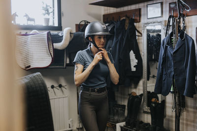 Woman putting riding cap to get ready for horseback riding