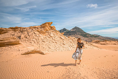 Full length of woman on arid landscape against sky