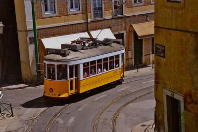 Yellow tram on road against buildings