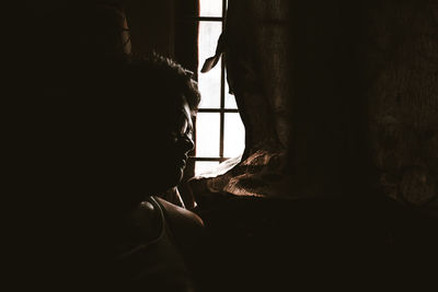Thoughtful silhouette man by window in darkroom