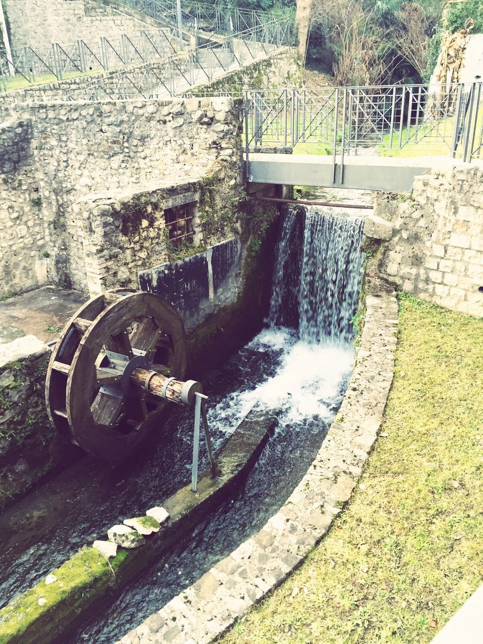 water, fountain, built structure, high angle view, day, outdoors, steps, no people, flowing water, metal, motion, architecture, park - man made space, railing, old, stone material, sunlight, grass, flowing, building exterior
