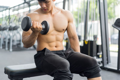 Midsection of shirtless man holding mobile phone