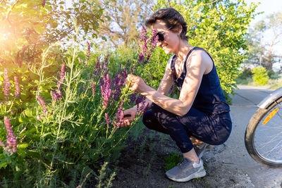 Side view of young man standing against plants