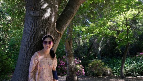 Young woman standing by tree at park