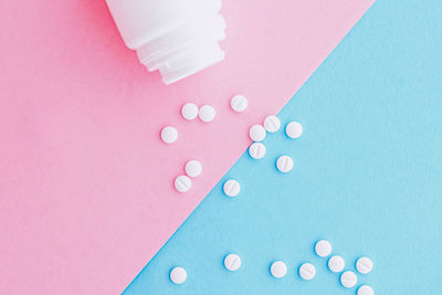 Close-up of pills spilling from bottle against blue background