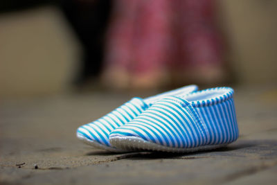 Close-up of baby shoes on the road where parents is standing in background