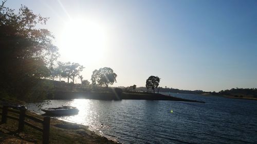 Statue at riverbank against clear sky