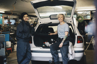 Portrait of a smiling couple standing on car