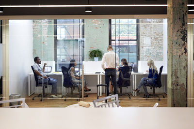 Business people working in office seen through glass wall