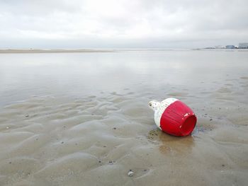 Red umbrella on beach against sky