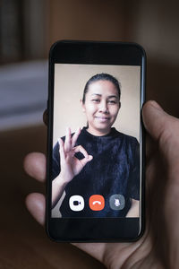 Woman on cell phone screen showing ok sign