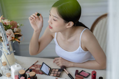 High angle view of woman apply make-up on table at home