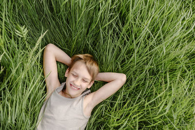 Happy boy with eyes closed lying down on grass