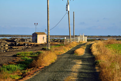 Dirt road by land against sky