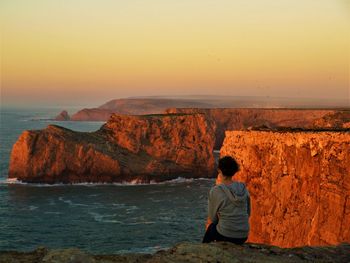 Rear view of man looking at sea against sky