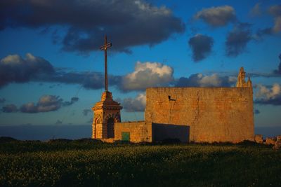 Buildings on field against sky during sunset