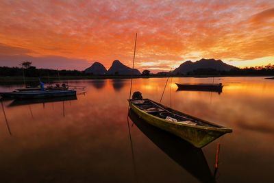 Sailboats moored on lake against sky during sunset