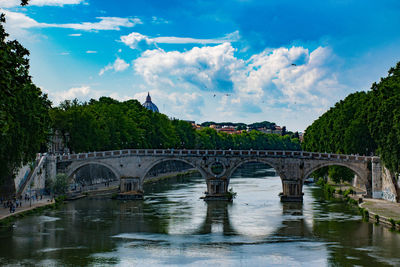 Ancient arch bridge over river against sky in rome