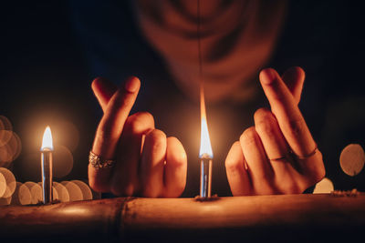Close-up of hand holding lit candles
