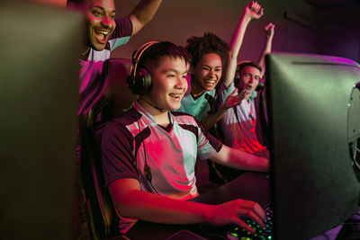 Rear view of friends using mobile phone while sitting on stage