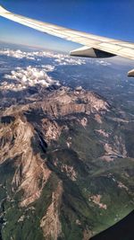 Aerial view of airplane wing over landscape against sky