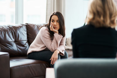 Young woman using phone while sitting on sofa at home