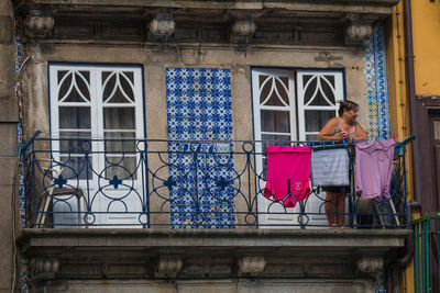 Woman standing by window of building