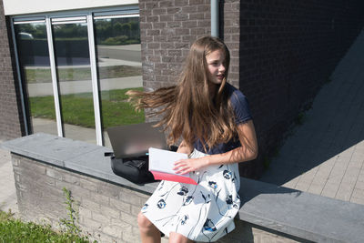 Portrait of young woman standing against wall