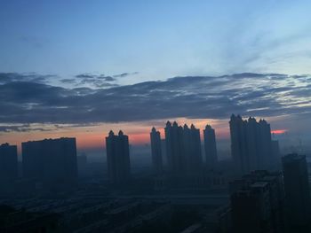 Buildings in city against sky during sunset