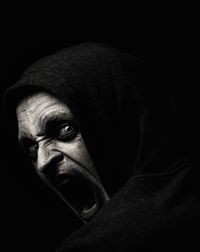 Portrait of scary man shouting against black background