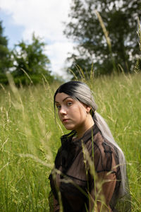 Young woman looking away while standing on field