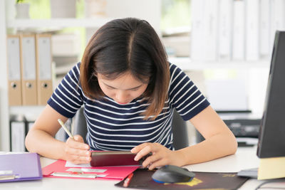 Woman looking at camera while sitting on table