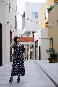 Woman standing on footpath amidst buildings in city