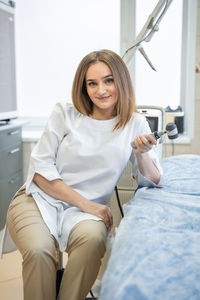 Portrait of young woman sitting on sofa at home