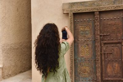 Rear view of woman standing against wall