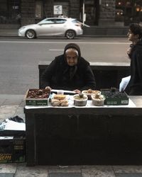 People sitting by car on street in city