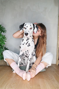 Midsection of woman with dog sitting on hardwood floor