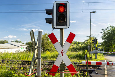 Guarded railroad crossing with closed barriers, red warning light and cross of saint andrew.