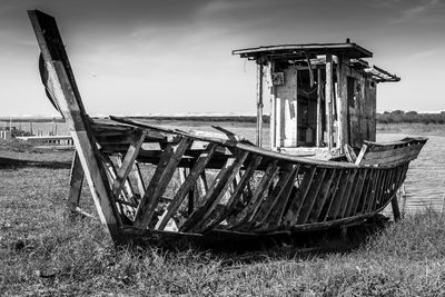 Abandoned boat on field against sky