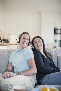 Happy couple listening music on sofa at home