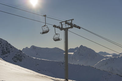 Low angle view of overhead cable car over snow covered mountain against sky