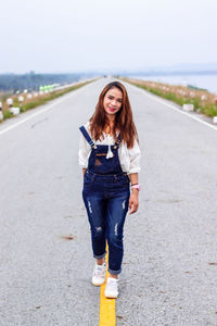 Portrait of smiling young woman standing on road