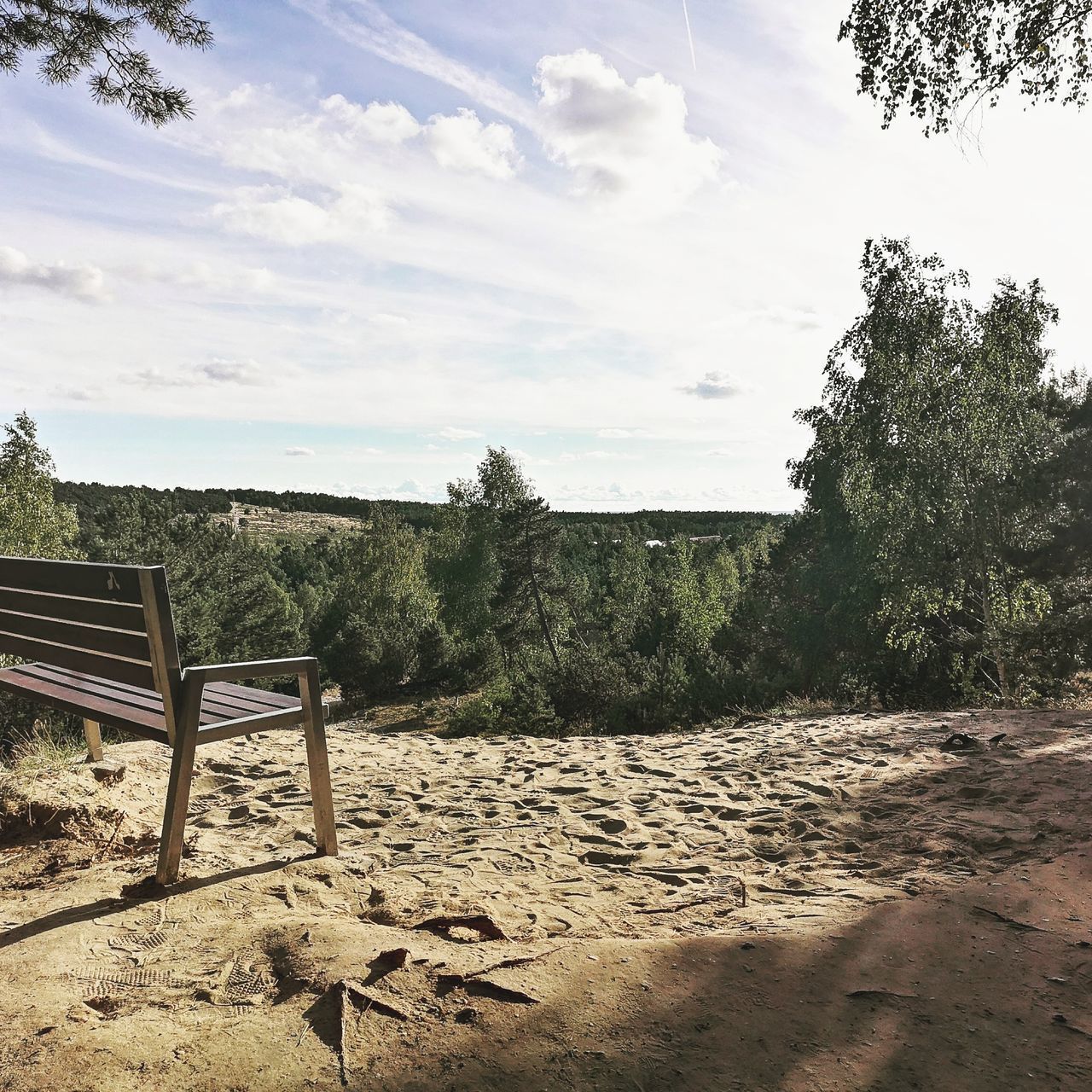 EMPTY BENCHES ON SAND AGAINST SKY