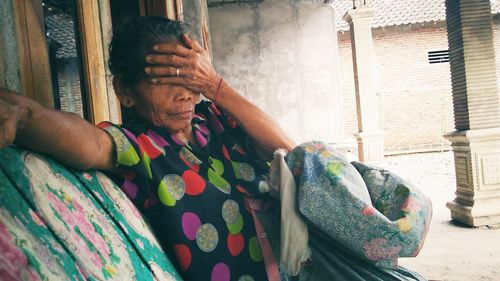 Midsection of woman sitting by window against building